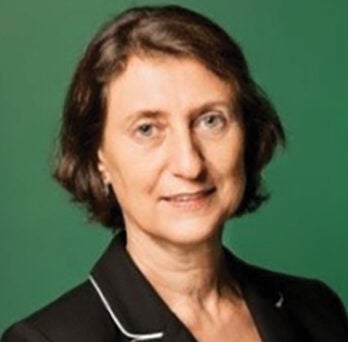 UIC Clinical Professor Eliane Karsaklian smiles at camera with green background 